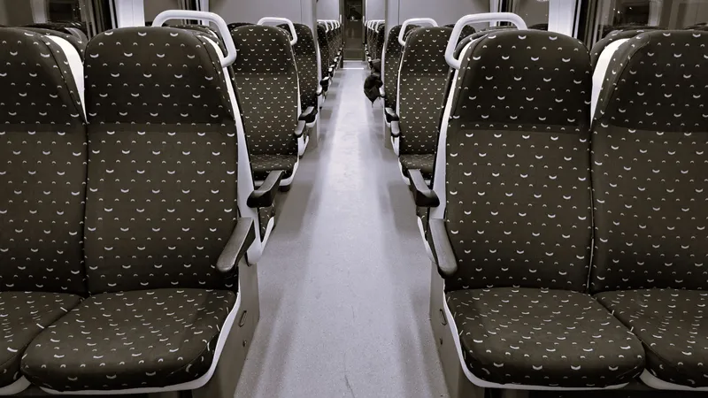 Interieur van een leeg treinrijtuig met rijen stoelen met motief en een gangpad in het midden