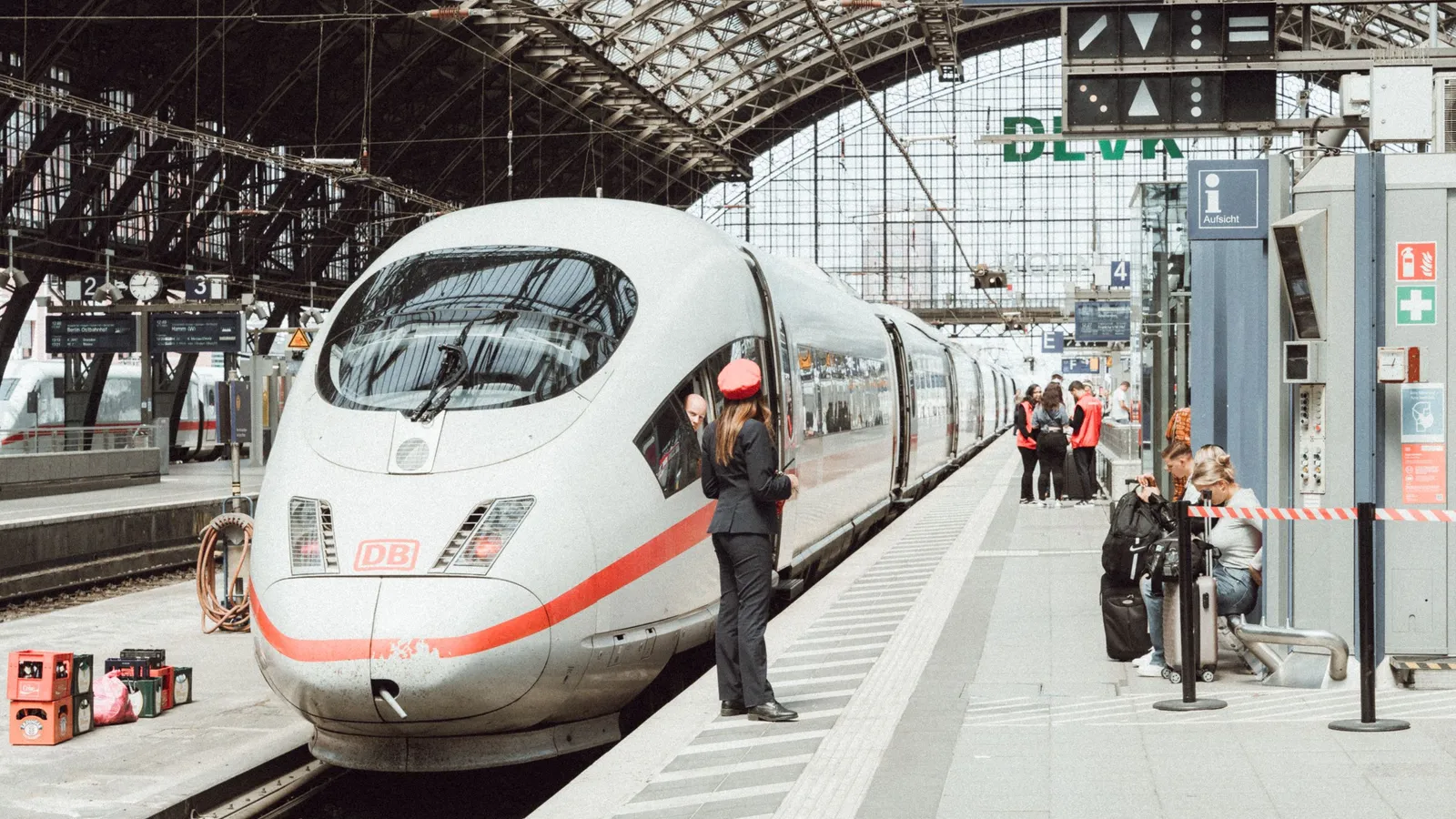 ICE-hogesnelheidstrein die klaarstaat op een Duits stationsperron, met een conducteur en wachtende reizigers