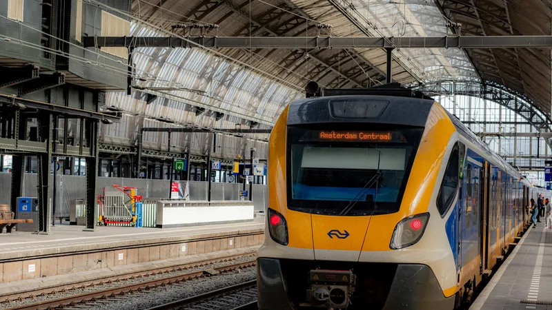 NS-trein op Amsterdam Centraal met bestemmingsscherm ‘Amsterdam Centraal’ onder het gewelfde perrondak