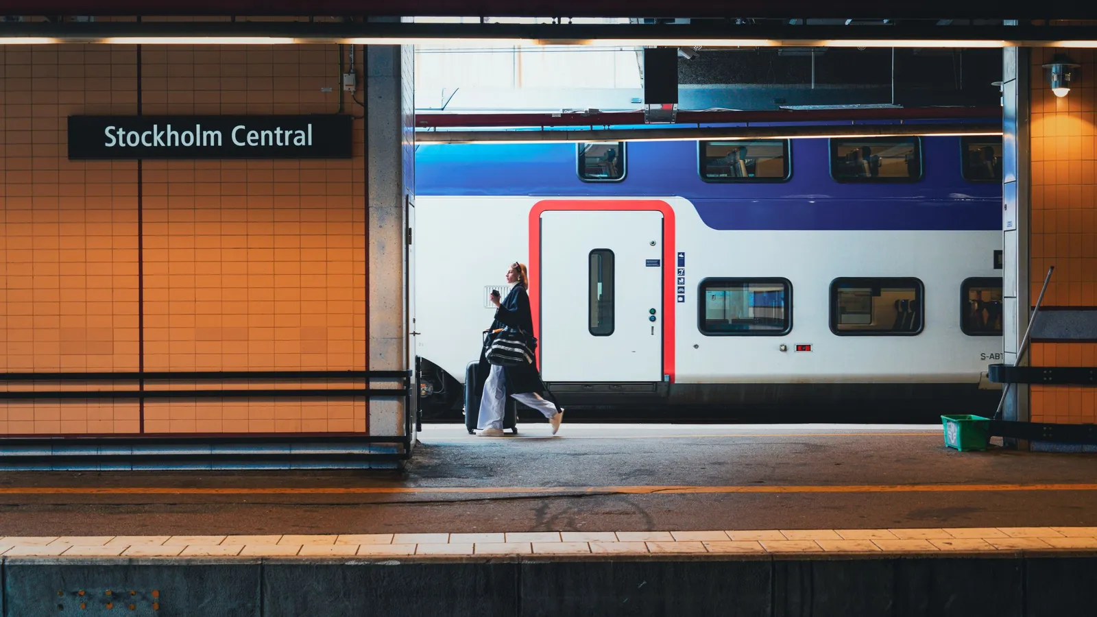 Reiziger trekt een koffer langs een wachtende trein op het perron van Stockholms centralstation