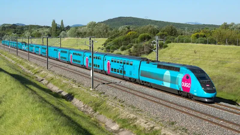 Tren Ouigo azul viajando por el campo