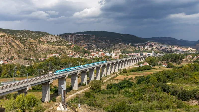 Een wit met turquoise HT80000-hogesnelheidstrein van TCDD Taşımacılık rijdt over het lange betonnen viaduct boven het stadje Bilecik in het noordwesten van Turkije.