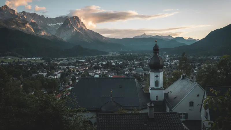 Garmisch-Partenkirchen bij schemering, een kerktoren tussen daken onder het Wettersteingebergte en de Zugspitze