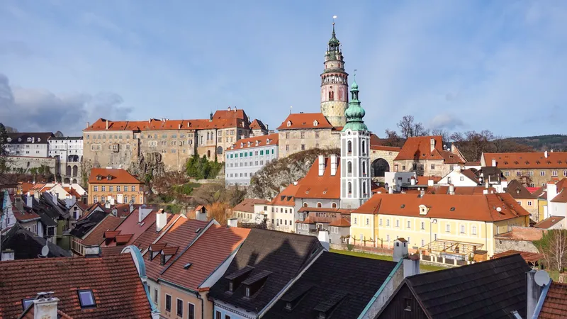 Kasteeltoren van Český Krumlov boven de rode daken van de oude stad onder een blauwe hemel