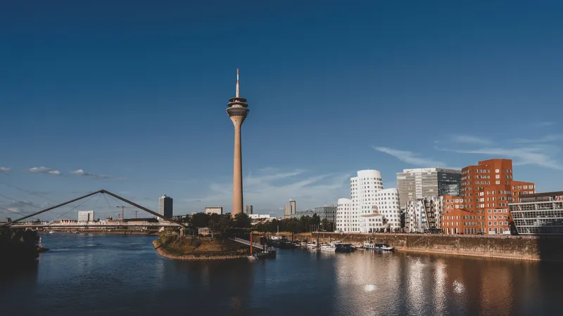 De Rheinturm en de Gehry-gebouwen van de MedienHafen weerspiegeld in de Rijn bij Düsseldorf in het licht van de late middag