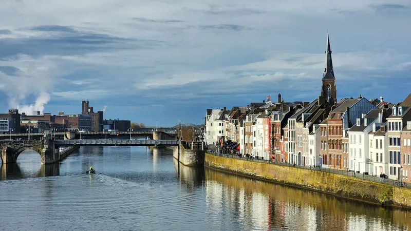 Historische panden aan de Maasoever in Maastricht met in de verte een stenen brug