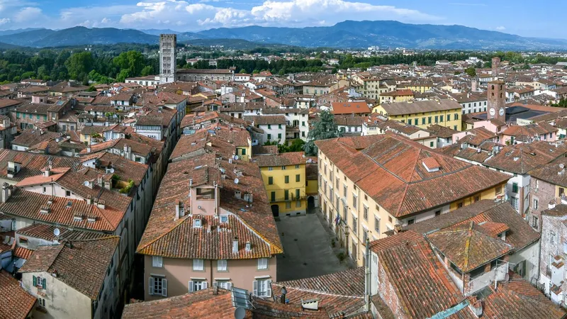 De terracotta daken en historische torens van Lucca onder de Toscaanse heuvels.
