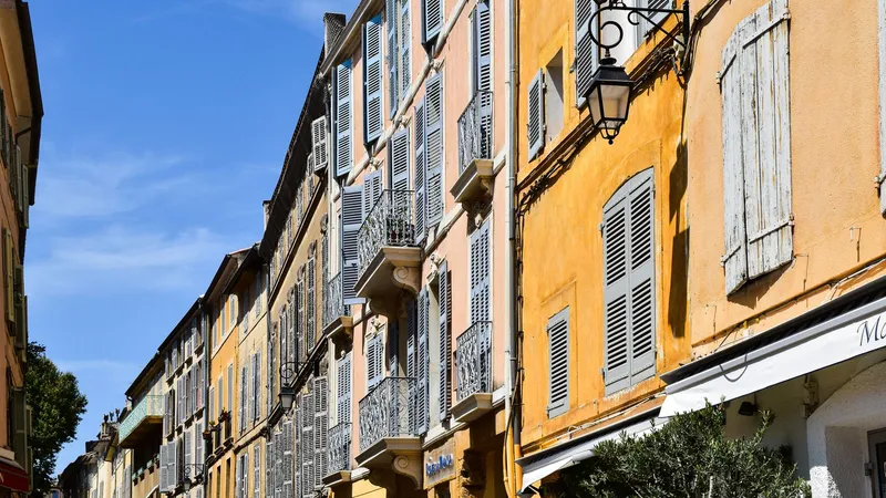 Historische okerkleurige gevels en ramen met luiken aan een zonnige straat in Aix-en-Provence.