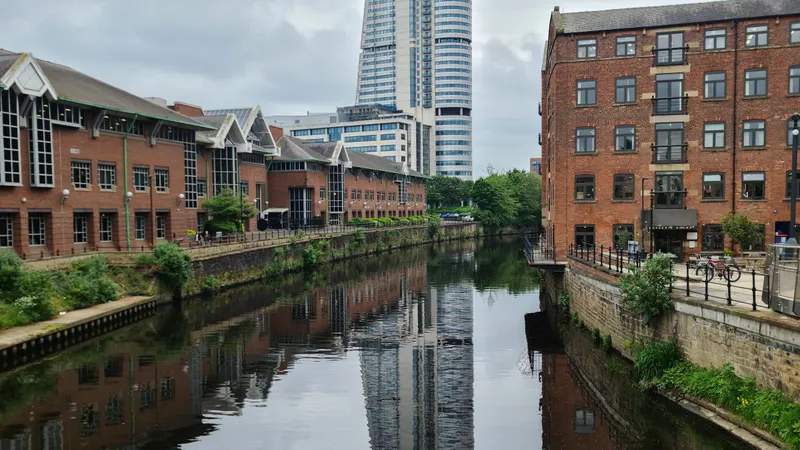 Bakstenen gebouwen en de toren Bridgewater Place weerspiegeld in het water in het centrum van Leeds