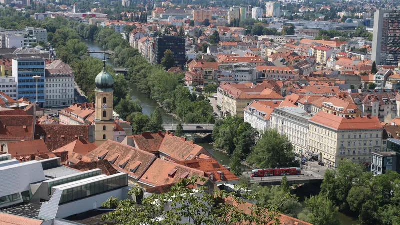Rode daken van de oude stad van Graz, een kerktoren en de Mur, van bovenaf gezien
