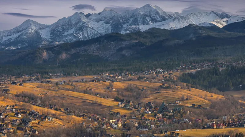 Besneeuwde Tatra-toppen boven houten huizen en herfstweiden bij Zakopane in Polen