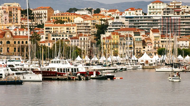 De haven van Cannes vol jachten, gebouwen aan het water en heuvels op de achtergrond.