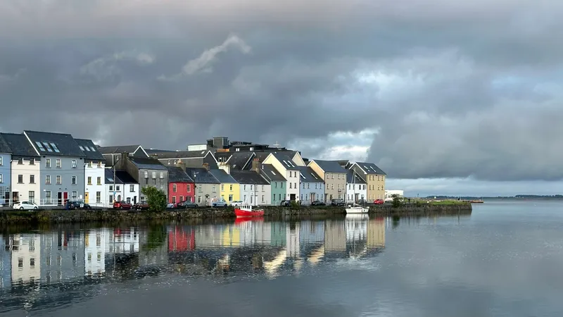 Kleurrijke rijtjeshuizen van de Long Walk weerspiegeld in het water bij Galway, Ierland