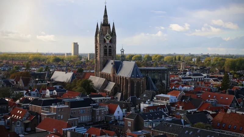Daken van de binnenstad van Delft met een historische kerktoren die erboven uitsteekt