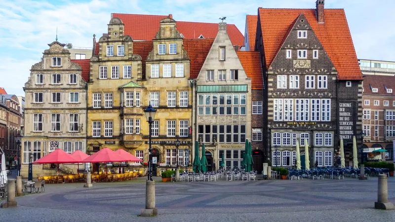 Historische gildehuizen met puntgevels aan de Marktplatz van Bremen onder een blauwe lucht, met terrasparasols beneden