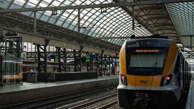 Een gele NS-trein op Amsterdam Centraal onder het glazen dak van het station