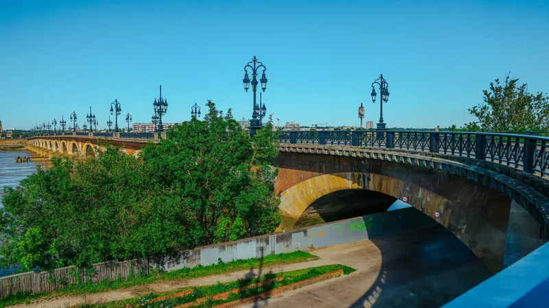 Stenen boogbrug met sierlijke lantaarnpalen over de Garonne in Bordeaux
