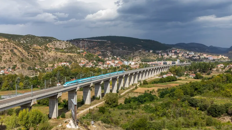 Un treno ad alta velocità HT80000 di TCDD Taşımacılık, bianco e turchese, attraversa il lungo viadotto in cemento sopra la città di Bilecik, nel nord-ovest della Turchia.