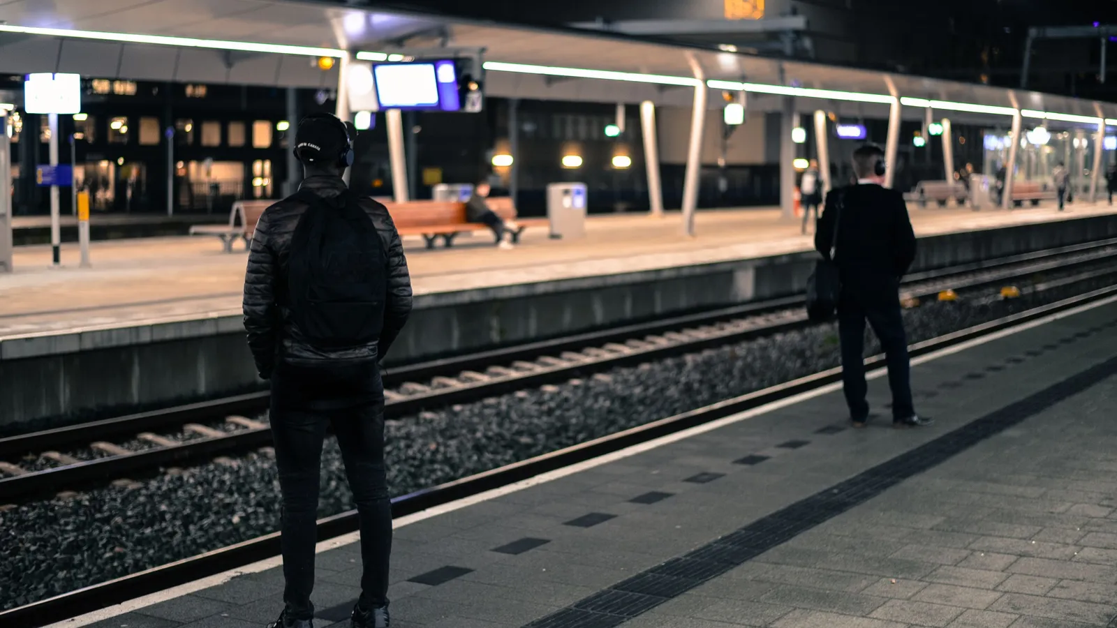 's Nachts wachten twee reizigers alleen op een verlicht perron in Nederland