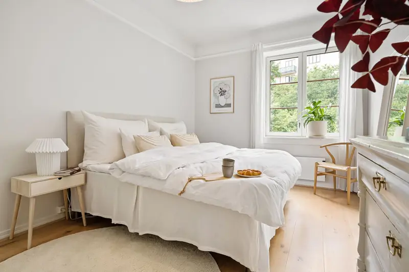 Lichte slaapkamer met wit beddengoed en een ontbijtblad op het bed