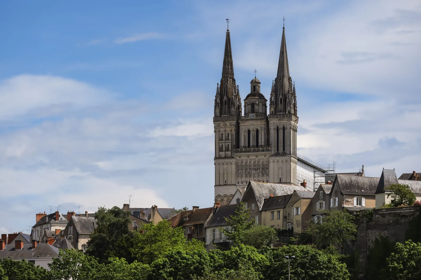 Twin spires of Angers Cathedral (Saint-Maurice) rising above the rooftops of the old town under a blue sky