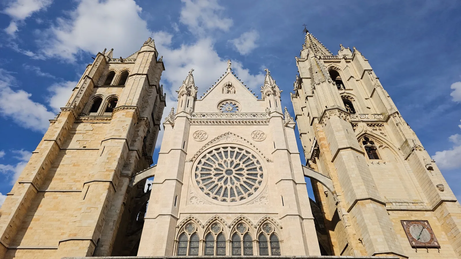 West façade of León Cathedral with its rose window and two towers against a blue sky