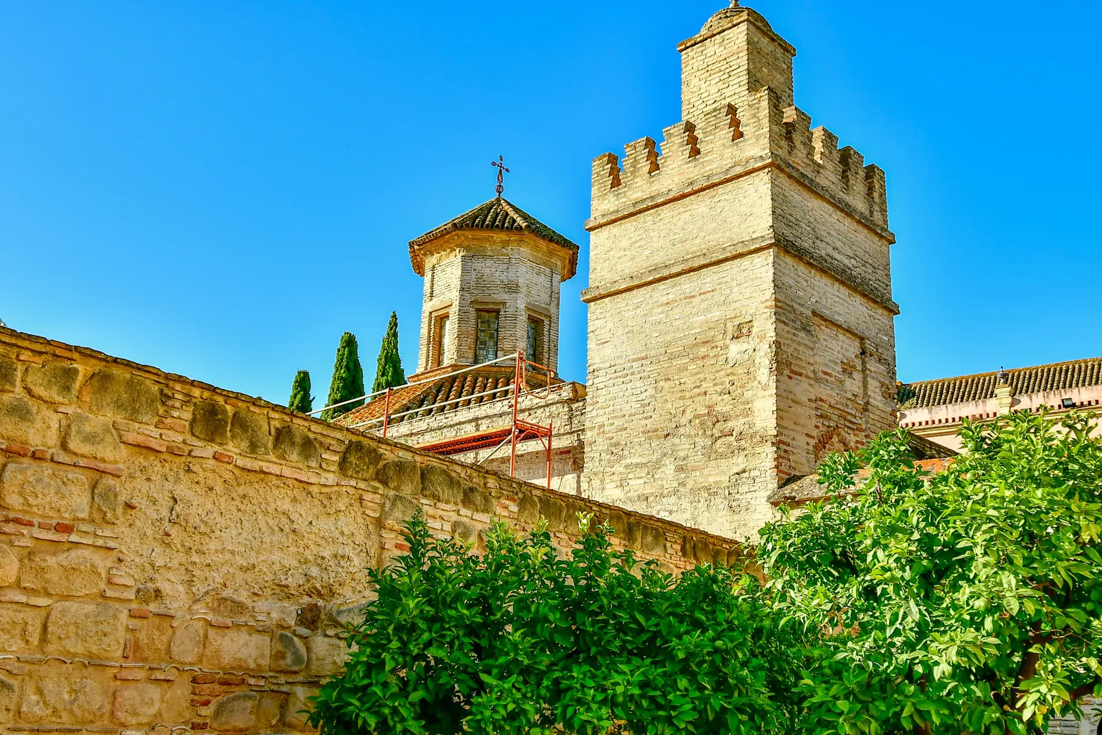 La torre merlata in pietra e le mura dell'Alcázar di Jerez de la Frontera sotto un cielo azzurro