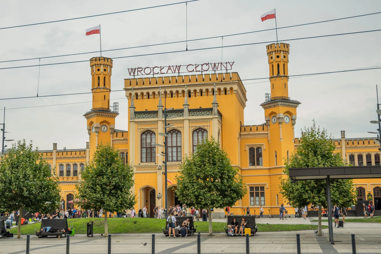 The ochre facade of Wrocław Główny railway station in Poland, with Polish flags flying above its twin towers